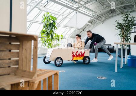 Männliche Kollegen mit Spielzeugauto im Kreativbüro Stockfoto