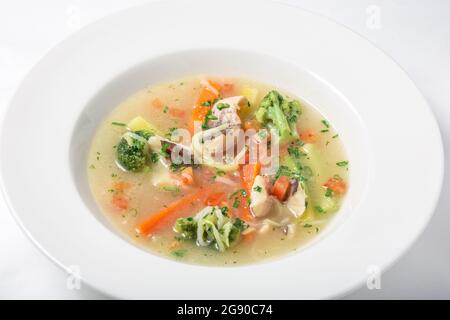 Leichte Fischsuppe mit Gemüse und Brokkoli in weißem Teller. Stockfoto