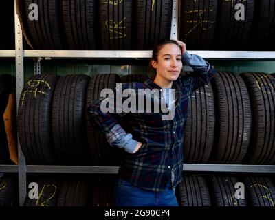 Mechanikerin, die sich in der Werkstatt auf den Reifenträger stützt Stockfoto