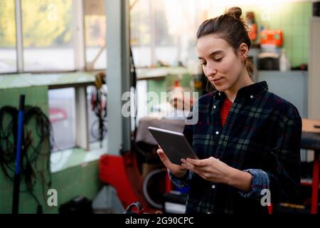 Mechanikerin mit digitalem Tablet in der Werkstatt Stockfoto