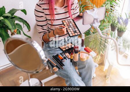 Weibliche Vloggerin macht Make-up-Tutorial durch Handy zu Hause Stockfoto