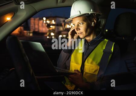 Professionelle in-Ear-Kopfhörer für Frauen, die den Laptop im Auto halten Stockfoto