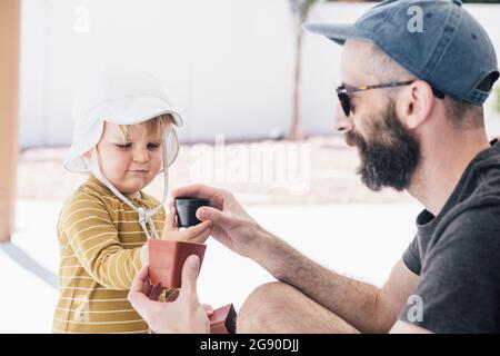 Bärtiger Mann, der während des Urlaubs am sonnigen Tag mit seinem Sohn auf der Terrasse spielte Stockfoto