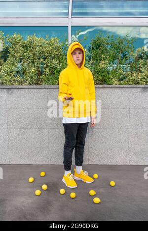 Junge hält Gummiente, während er inmitten von Zitronen steht Stockfoto