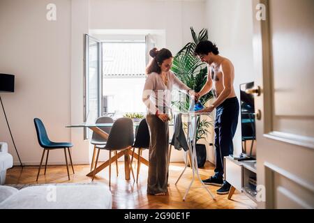 Frau hilft Mann zu Hause beim Bügeln Stockfoto