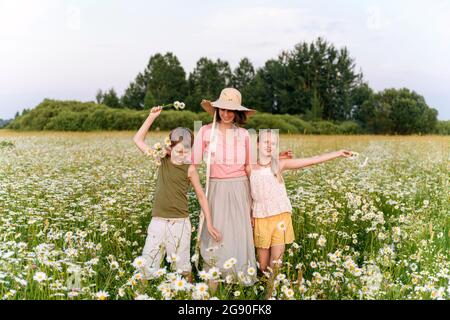 Mutter steht mit Kindern inmitten von Blumen auf dem Feld Stockfoto