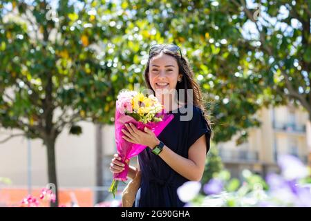 Schöne Frau hält Blumenstrauß im Blumenladen Stockfoto