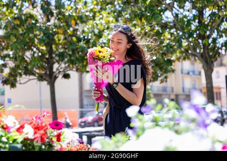 Lächelnde Frau mit Blumenstrauß im Blumenladen Stockfoto