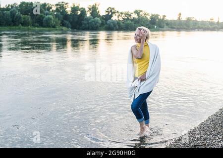 Reife Frau mit Decke, die im Fluss läuft Stockfoto