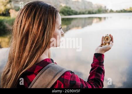 Junge blonde Frau mit Kompass am Seeufer Stockfoto