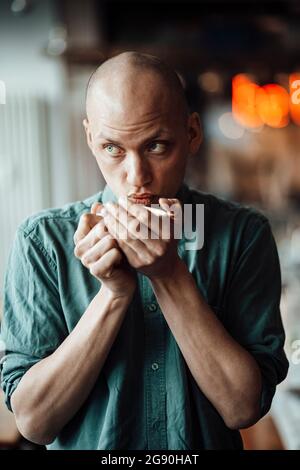 Männlicher Cafe-Besitzer schaut weg, während er Kaffee trinkt Stockfoto