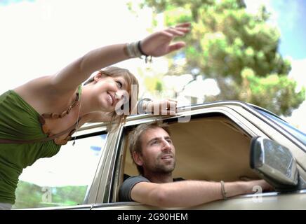 Lächelnde junge Frau, die dem Mann auf der Autofahrt den Weg zeigt Stockfoto