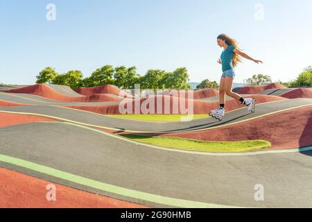 Junge Frau übt auf der Pumpstrecke Rollschuhlaufen Stockfoto