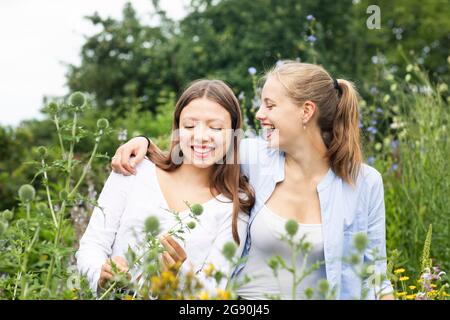 Fröhliche junge Frau mit Arm um Freund inmitten von Pflanzen in der Natur Stockfoto