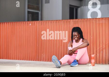 Lächelnde und große Frau, die Smartphone auf dem Weg benutzt Stockfoto