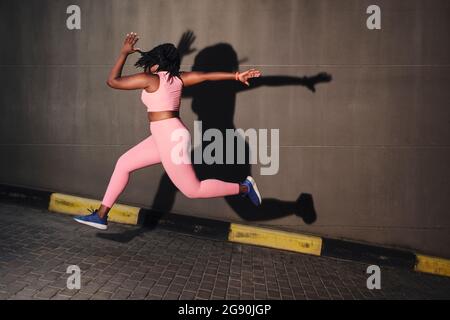 Plus Größe junge Frau springen über Straße Stockfoto