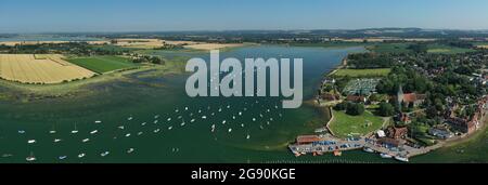 Bosham Village mit Booten, die in der Mündung in der wunderschönen Landschaft von West Sussex in Südengland festgemacht sind. Luftpanoramabbild. Stockfoto