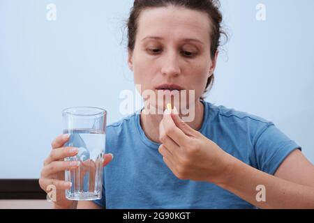 Eine Frau nimmt eine Kapsel Medizin. Konsum der Droge. Behandlung der Krankheit. Stockfoto