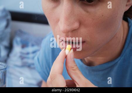 Eine Frau nimmt eine Kapsel Medizin. Konsum der Droge. Behandlung der Krankheit. Stockfoto