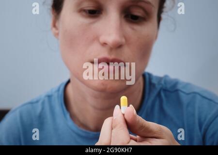 Eine Frau nimmt eine Kapsel Medizin. Konsum der Droge. Behandlung der Krankheit. Stockfoto