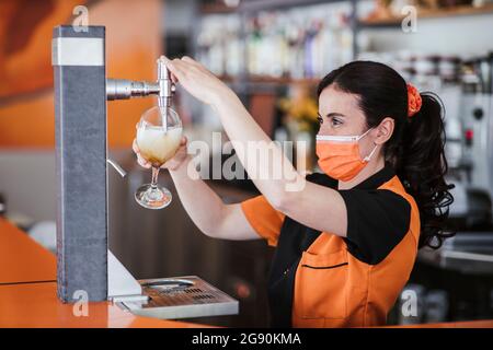 Kellnerin füllte während einer Pandemie Bierglas vom Zapfhahn an der Bar Stockfoto