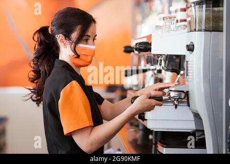 Kellnerin hält einen Portafilter mit Espressomaschine in der Cafeteria Stockfoto