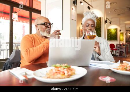 Männliche und weibliche Geschäftsleute, die Getränke im Restaurant genießen Stockfoto