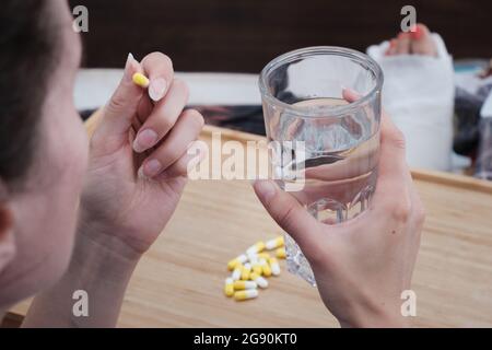 Eine Frau nimmt eine Kapsel Medizin. Konsum der Droge. Behandlung der Krankheit. Stockfoto