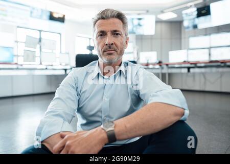 Geschäftsmann starrte, während er im Kontrollraum saß Stockfoto