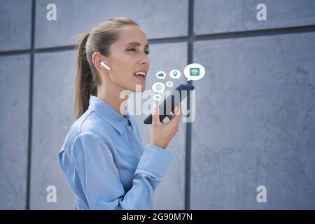 Geschäftsfrau mit schnurlosen in-Ear-Kopfhörern, die ein Mobiltelefon sprechen Stockfoto