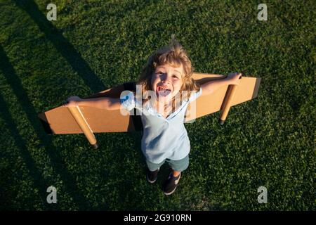 Aufgeregt Kind mit Rucksack Flügel. Kind spielt Flieger und träumt im Park. Lächelndes Kind träumt von Sommerurlaub und Reisen. Junge d Stockfoto