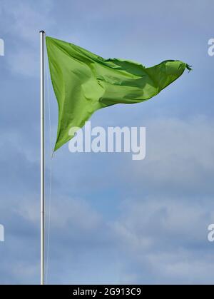 Eine dreieckige grüne Flagge über einem wolkigen Himmel. Stockfoto