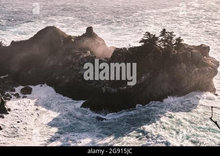 Wellen krachen am Sonnentag im Big Sur gegen die Felsstruktur im Ozean Stockfoto