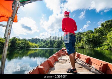Mann, der den Tatai auf einem langen Boot in Kambodscha erkundet Stockfoto