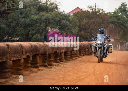 Mann, der in Kambodscha auf seinem Abenteuer-Motorrad über die Drachenbrücke fährt Stockfoto