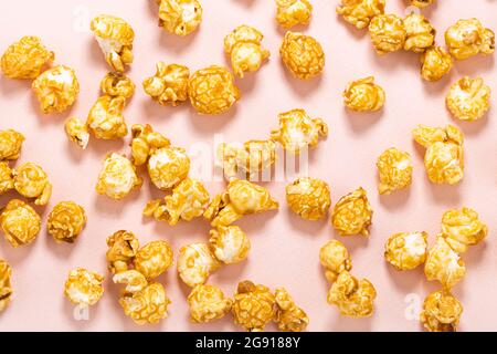 Karamellfarbenes Popcorn auf pastellrosa Hintergrund. Stockfoto
