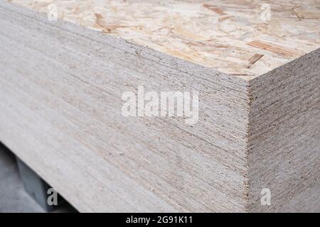 Der Stapel der OSB-Platten wird in einem Baumarkt auf einer Palette gestapelt. Sperrholz mit Fragmenten von komprimiertem Sägemehl, für den Bau vorbereitet. Selektiv Stockfoto