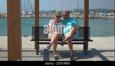 Familienpaar mit Unterlage am Wasser Stockfoto
