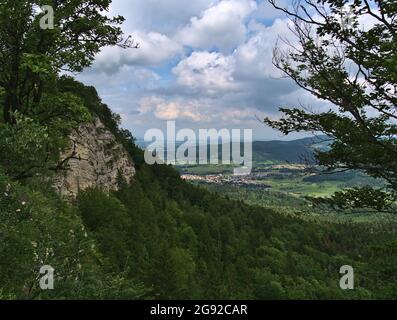 Felswand am Rande ('Albtrauf') der Niedergebirgsalbe Schwäbische Alb durch Bäume mit grünen Wäldern und den östlichen Teil der Stadt Balingen gesehen. Stockfoto