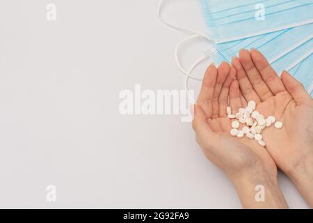 Eine Handvoll weißer Pillen in den beiden Händen einer jungen Frau Stockfoto