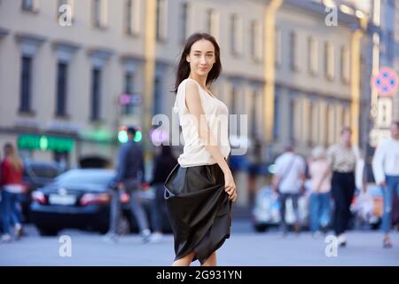 Schlanke Frau im schwarzen Rock geht im Sommer draußen. Stockfoto