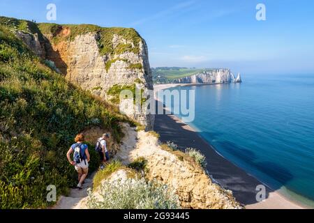 Ein paar ältere Touristen gehen die Felstreppe hinunter zum Strand am Fuße der Amont-Klippe in Etretat, Normandie. Stockfoto