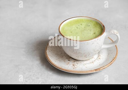 Matcha Tee Latte Nahaufnahme auf einem grauen Betonhintergrund. Japanischer grüner Tee. Speicherplatz kopieren Stockfoto