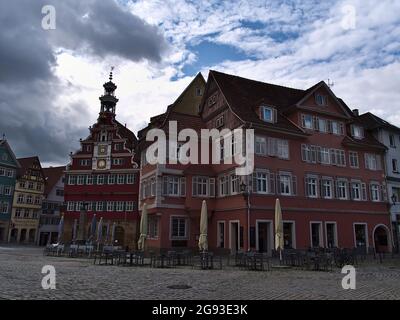 Stadtbild des historischen Zentrums von Esslingen mit altem Rathaus (links) mit roter Fassade, gelegen auf einem gepflasterten Platz mit leeren Sitzgelegenheiten im Freien eines Cafés. Stockfoto