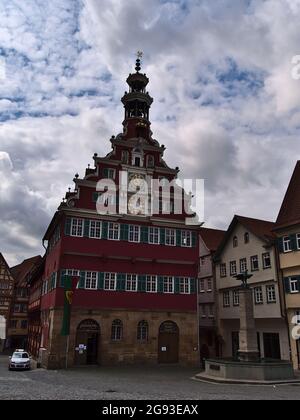 Altes Rathaus von Esslingen mit roter Fassade am Rathausplatz in der historischen Innenstadt, umgeben von alten Gebäuden am bewölkten Tag. Stockfoto