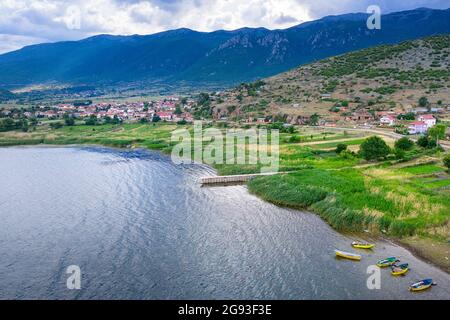 Blick aus der Vogelperspektive auf den See Prespa am Dreipunkt Nordmazedonien, Albanien und Griechenland, kleines Dorf umgeben von Bergen, Albanien Stockfoto