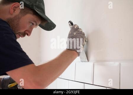 Der kaukasische Mann setzte Gips auf, um die Risse an der Wand zu flicken. Stockfoto