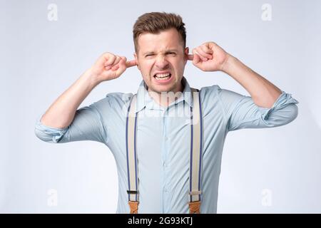 Kaukasischer junger Mann mit Fingern im Ohr und nicht hörender Expression Stockfoto