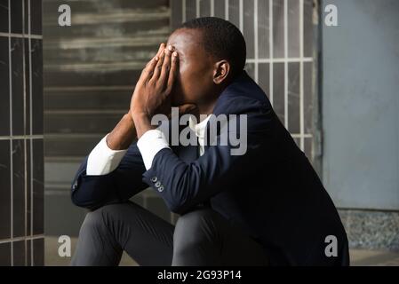 Junger Mann in Anzug sitzt depressiv traurig weinen verwüsteten Gefühl verletzt leiden an Depressionen. Depressionen bei Menschen, Traurigkeit, emotionaler Schmerz Stockfoto