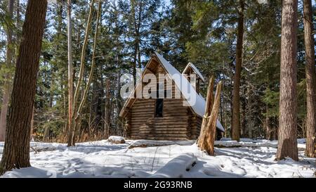 Winterdecke mit Schnee bedeckt den Boden rund um die Kapelle im Hartwick Pines State Park, in der Nähe von Grayling, Michigan. Stockfoto